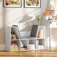 Ein weisses Bücherregal mit 6 Fächern und einem Sitzkissen in Leinenoptik.