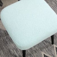 Ein hellblauer, quadratischer Fusshocker in Kaschmir-Optik mit Stahlbeinen.