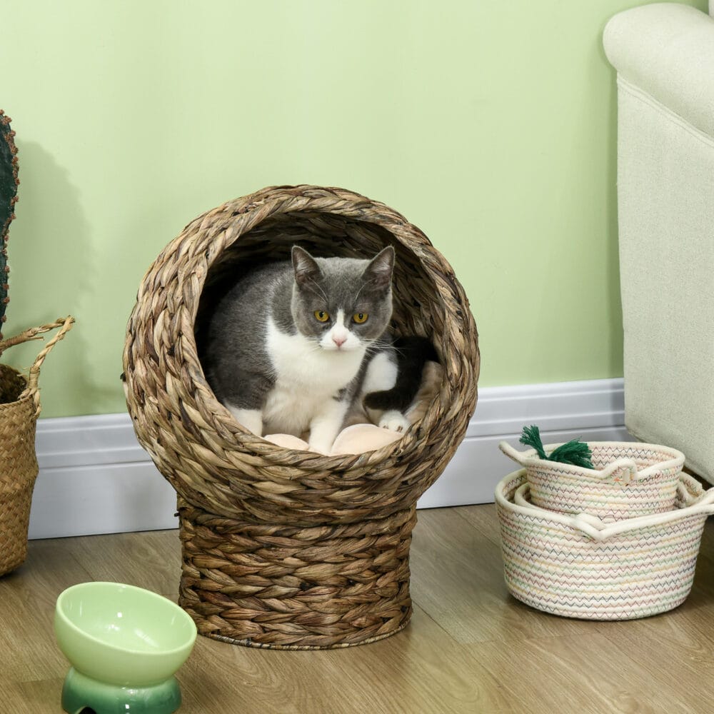 Dunkelbrauner Katzenkorb aus Rattan mit Kissen aus Wasserhyazinthe, bietet eine natürliche und bequeme Schlafgelegenheit.