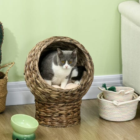 Dunkelbrauner Katzenkorb aus Rattan mit Kissen aus Wasserhyazinthe, bietet eine natürliche und bequeme Schlafgelegenheit.