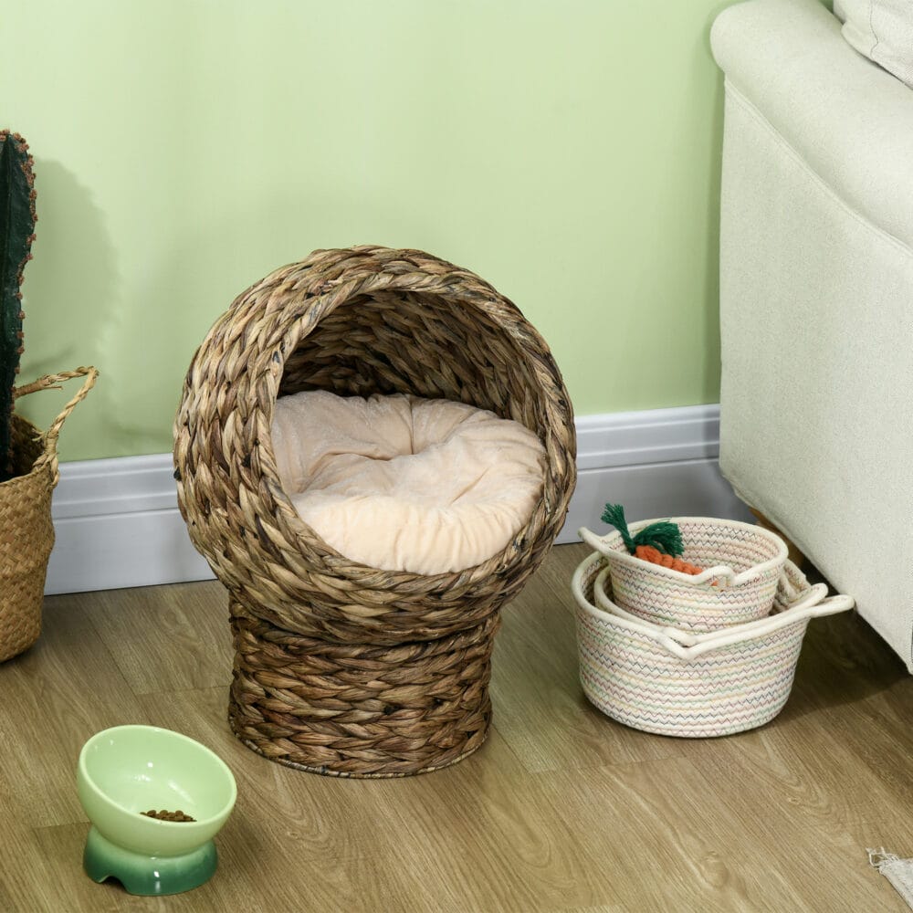 Dunkelbrauner Katzenkorb aus Rattan mit Kissen aus Wasserhyazinthe, bietet eine natürliche und bequeme Schlafgelegenheit.