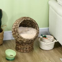 Dunkelbrauner Katzenkorb aus Rattan mit Kissen aus Wasserhyazinthe, bietet eine natürliche und bequeme Schlafgelegenheit.