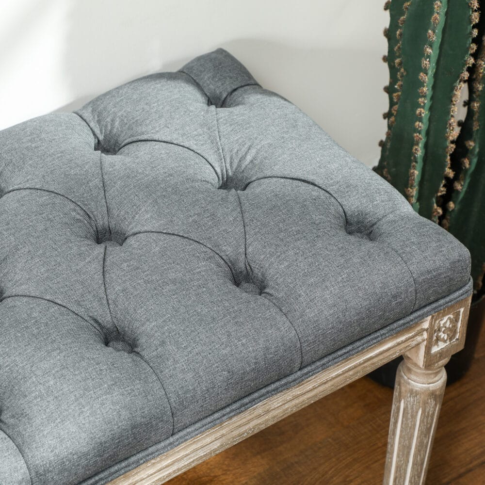 Graue Polsterbank im Vintage-Stil mit eleganter Knopfverzierung. Ein zeitloses Möbelstück für klassische Einrichtungen.