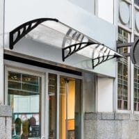 Transparentes Pultvordach für die Haustür, aus Polycarbonat und Aluminium, bietet modernen Wetterschutz.