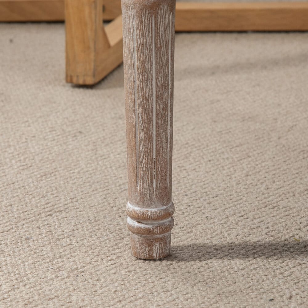 Ein cremeweisser Sitzhocker mit gepolstertem Sitz und Holzbeinen in Leinenoptik.