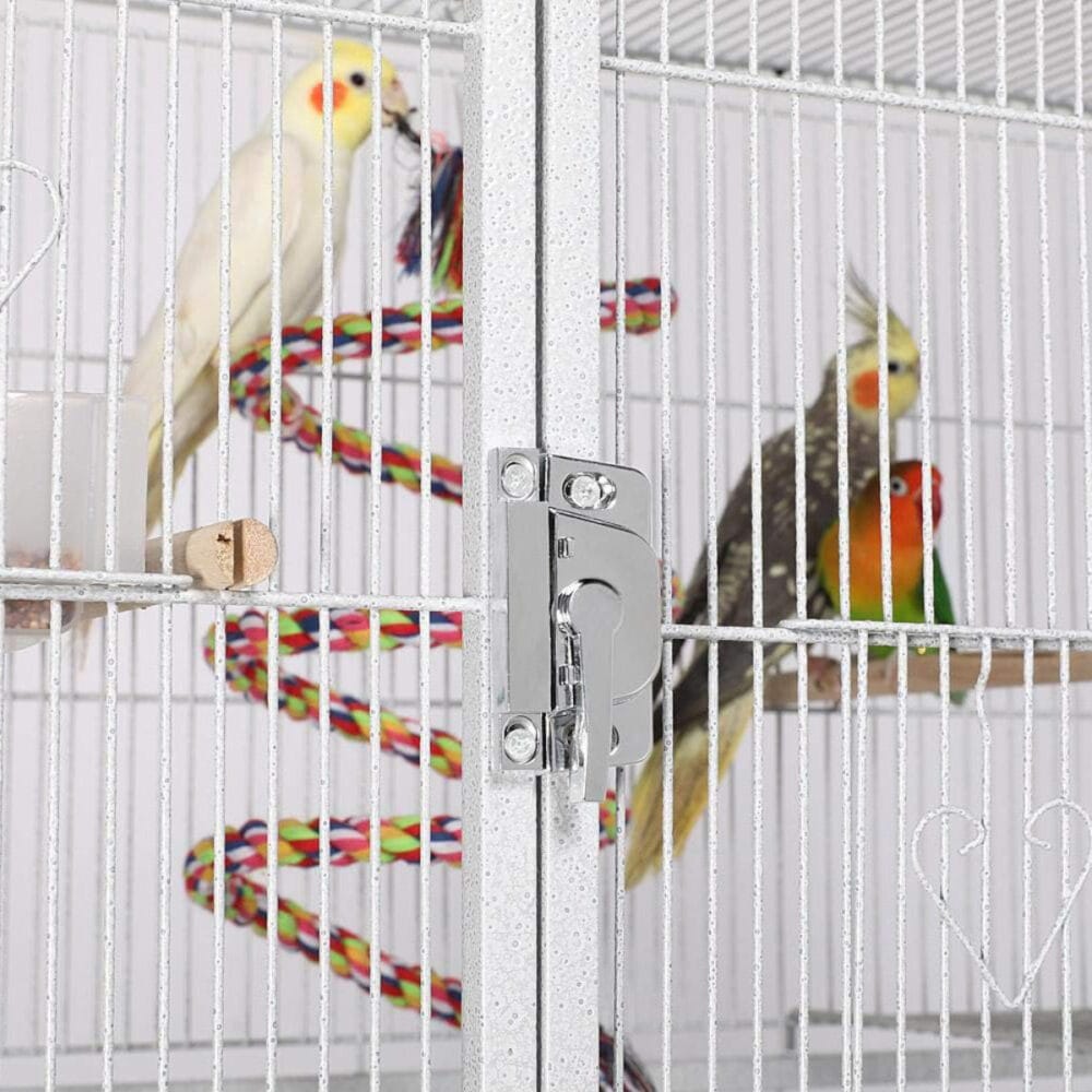 Nahaufnahme der stabilen Türverriegelung einer großen weißen Vogelvoliere mit buntem Kletterseilspielzeug – sicherer und robuster Vogelkäfig für Innenräume.